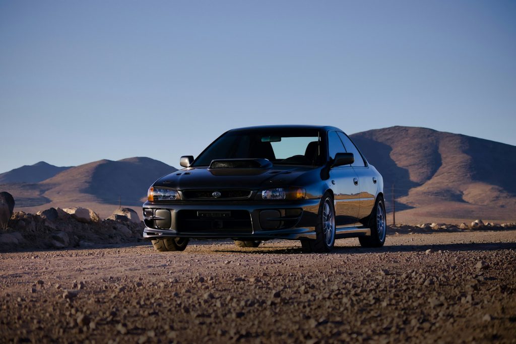 blue chevrolet camaro on brown sand during daytime