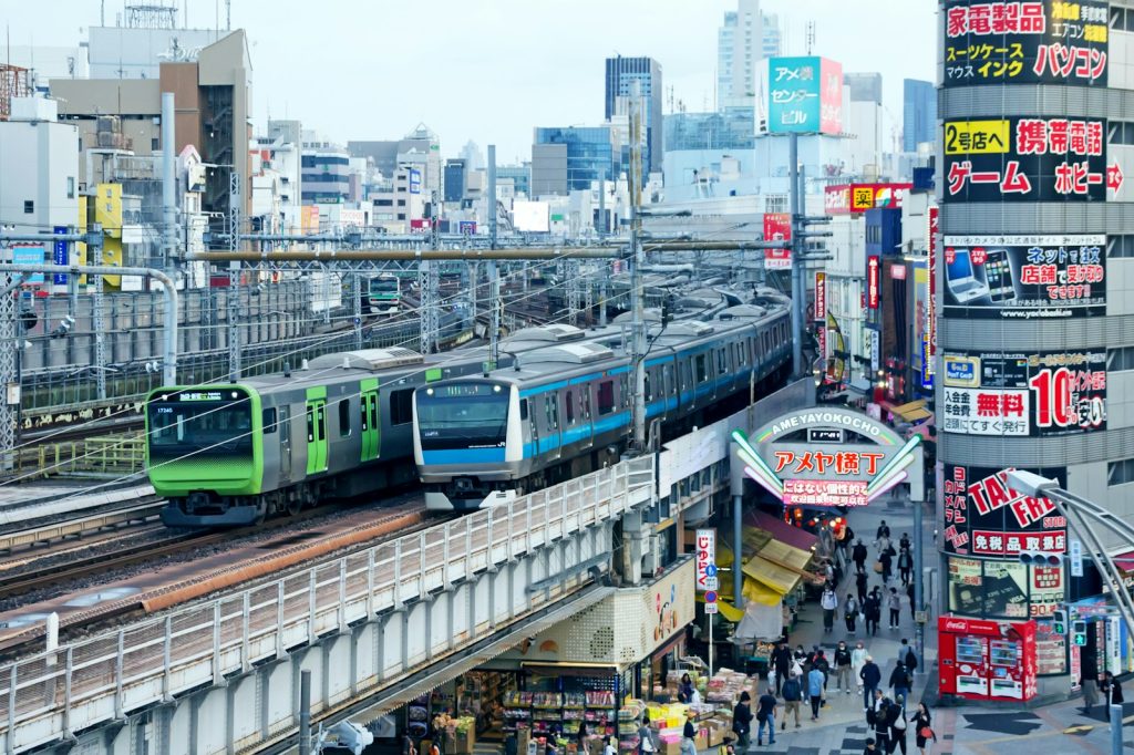 a green train traveling down train tracks next to tall buildings