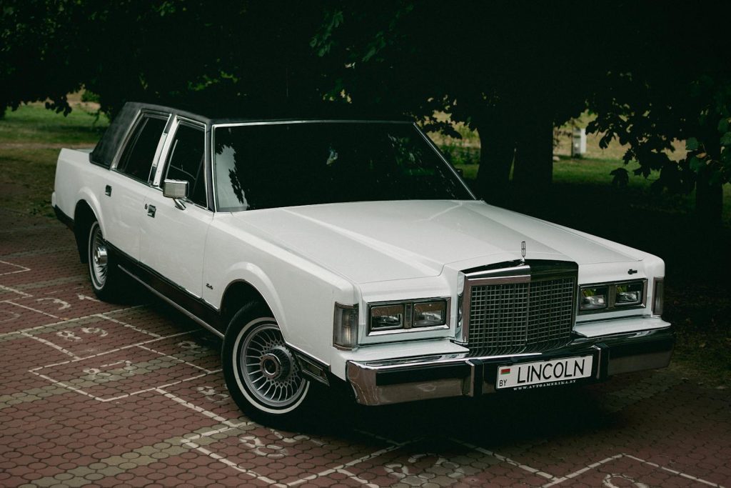 A white lincoln town car parked on a brick road