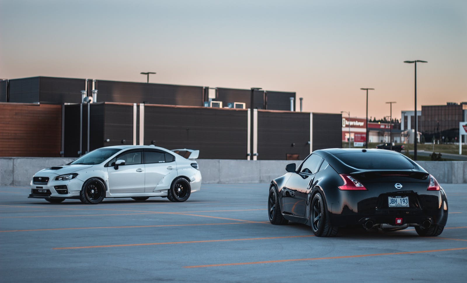 Black and white race cars on parking lot at sunset